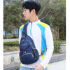 A young man wearing a white shirt and jeans holds a navy blue multi-functional nylon chest sling bag.