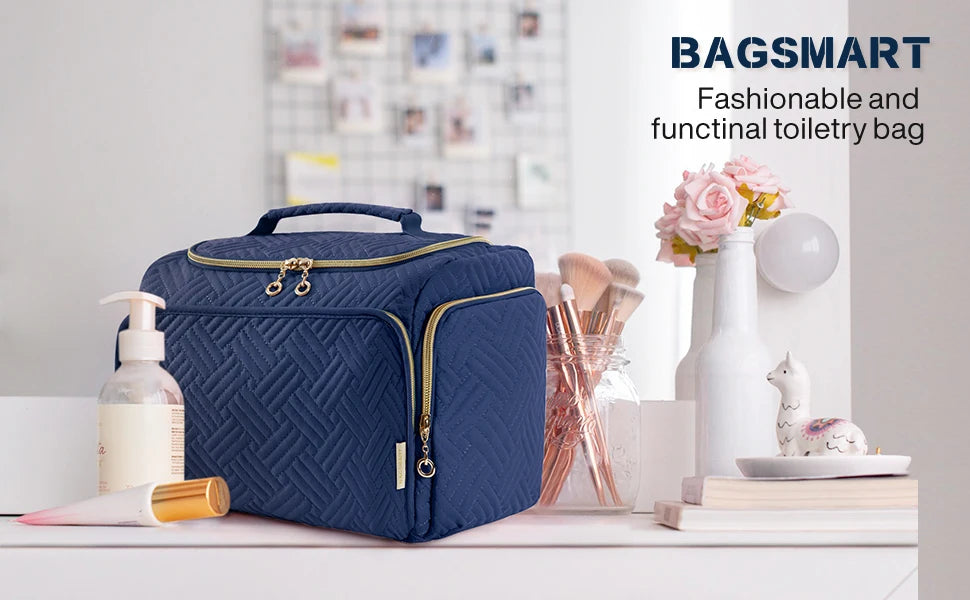 A navy blue bagsmart toiletry bag with a handle sits on a white surface next to various beauty products.