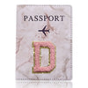 Una funda de pasaporte de mármol rosa con una letra D dorada grabada.