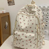 Mochila blanca con estampado floral de fresas rosas y múltiples bolsillos.