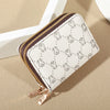 A white zippered card holder wallet with gold zipper and subtle gray geometric pattern resting on a beige surface.