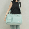 A light mint green quilted portable travel duffle bag carried by a person.