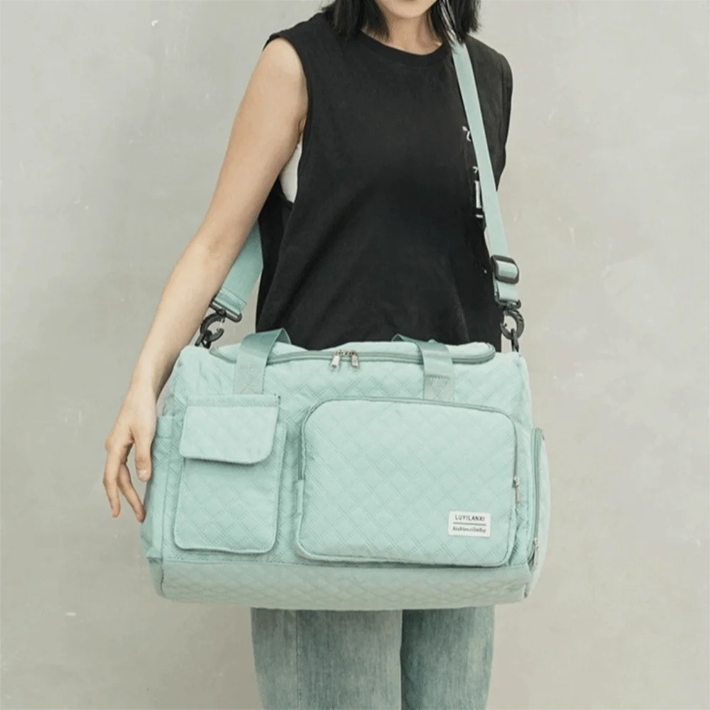 A light mint green quilted portable travel duffle bag carried by a person.