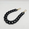 A black acrylic chain bracelet with gold-colored clasps.