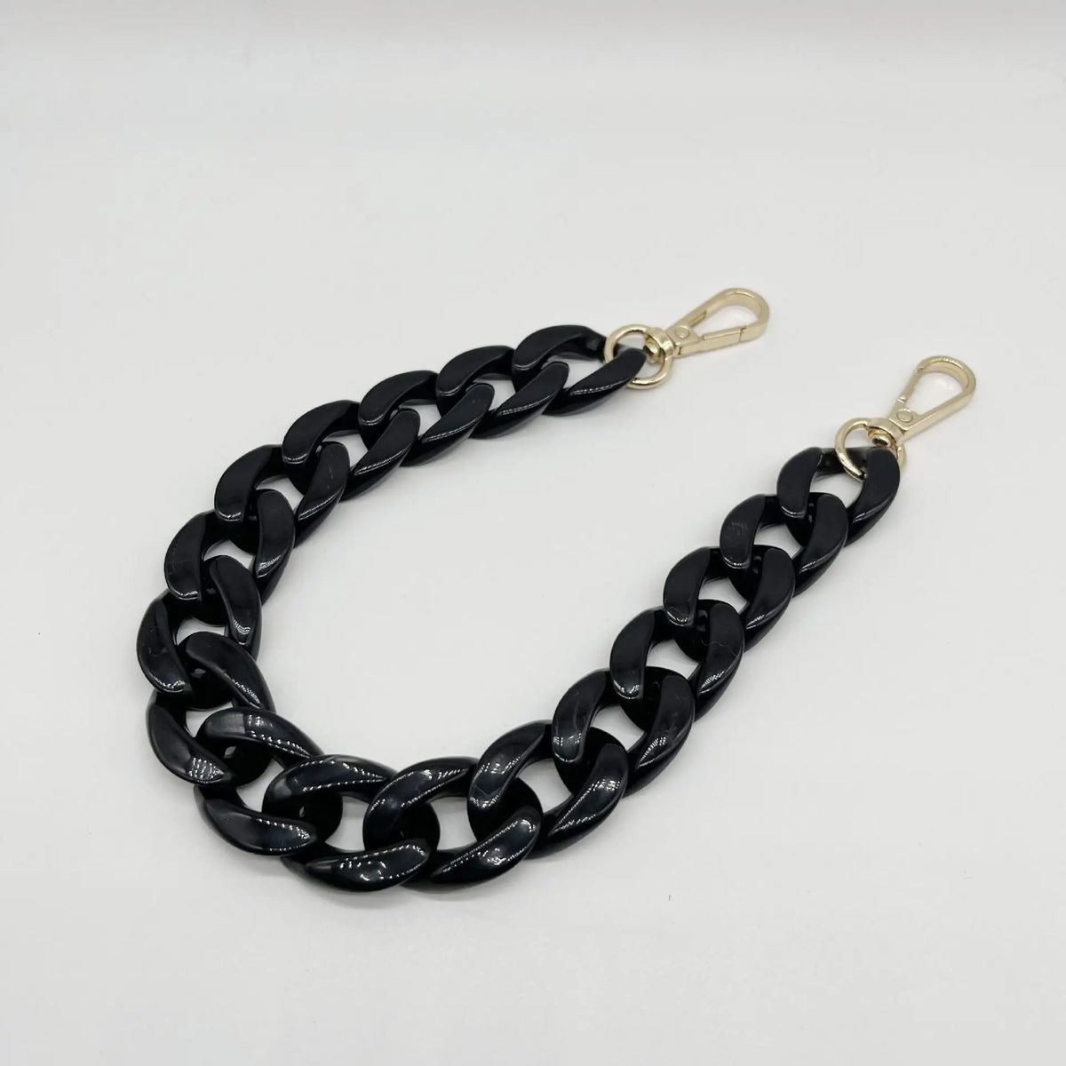A black acrylic chain bracelet with gold-colored clasps.