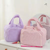 A pink multipocket travel toiletry bag is shown on a white surface.