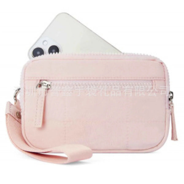 A light pink quilted crossbody bag with a zipper and strap is shown next to a smartphone.