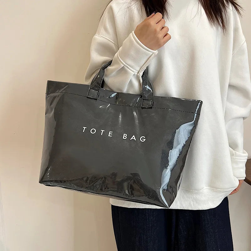 A person holds a black transparent waterproof PVC tote bag against a white background.