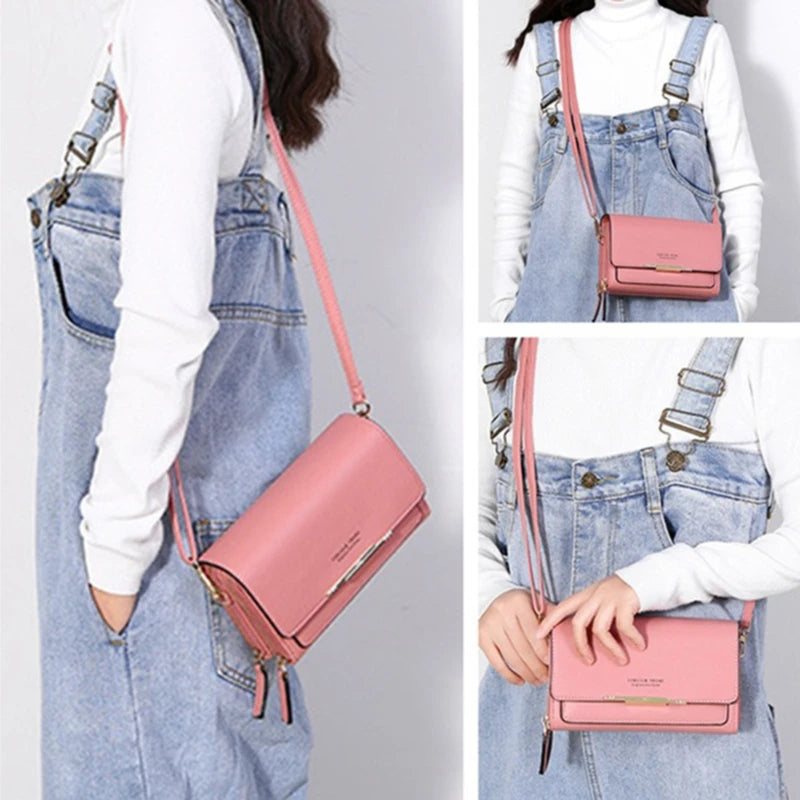 A woman wearing denim overalls and a white top, holding a pink multi-card shoulder wallet.