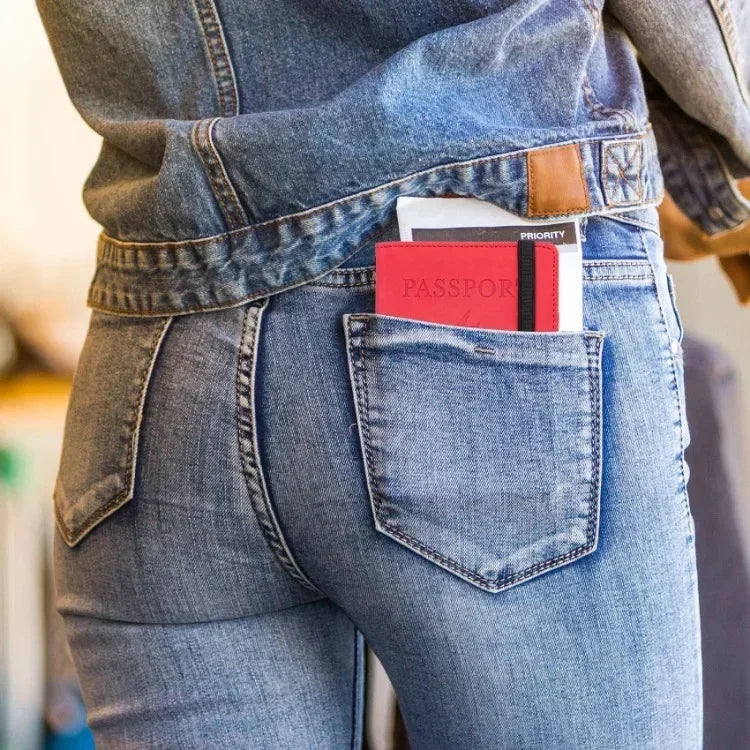A close-up of a person's jeans pocket showing an RFID blocking leather travel wallet and passport.