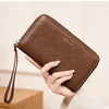A brown slim RFID-blocking PU leather wallet with a zipper closure is shown being held and opened to display credit cards.
