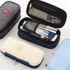Collection de trousses et poches en toile grise, bleu marine et bleu clair.