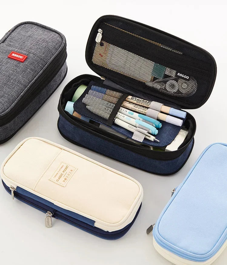 Collection de trousses et poches en toile grise, bleu marine et bleu clair.