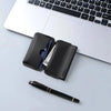 A black magnetic foldable ID card holder and coin purse resting on a white laptop keyboard.