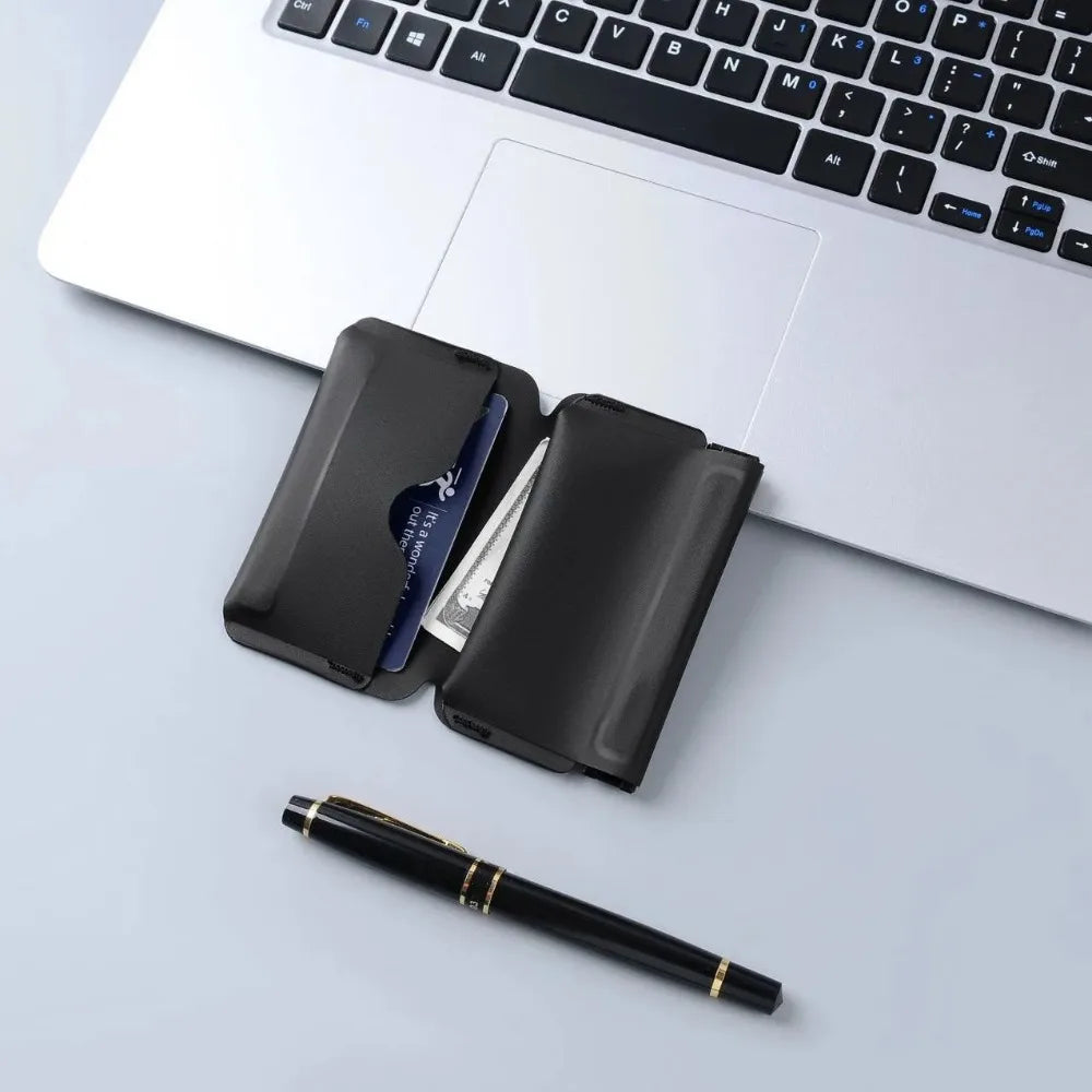 A black magnetic foldable ID card holder and coin purse resting on a white laptop keyboard.