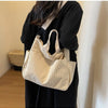 A woman holds a beige corduroy multi-pocket tote bag against a black outfit.