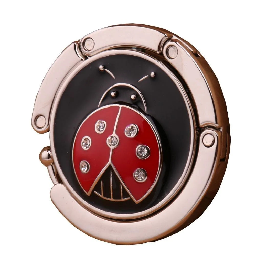 Ganchillo para mesa de mariposa de metal dorado rosa con diseño negro y rojo.