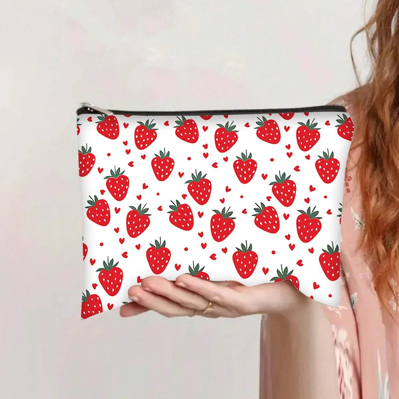 Bolsa de almacenamiento cosmético rosa con estampado repetitivo de fresas rojas sobre fondo blanco.