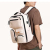 A person is wearing a beige travel backpack with black accents, displayed against a white background.