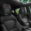 Dos protectores de cabezal de animales negros con ojos rojos brillantes instalados en el interior de un coche.