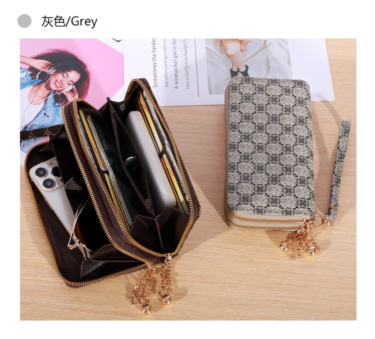 Cartera con cremallera de cuero sintético gris abierta, mostrando un smartphone y una cartera a juego estampada.