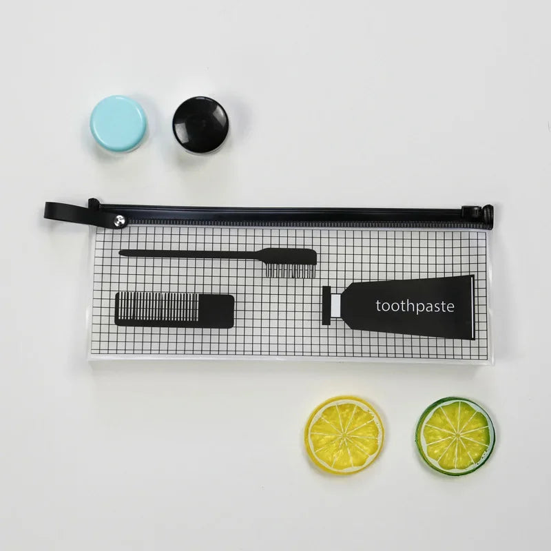 Bolsa transparente de cosméticos para viajar con espátula negra y cepillo de dientes sobre una superficie de rejilla, junto a