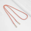 Pink and gold chain strap with buckle for bags lying on a white surface.