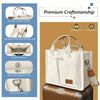 A cream canvas tote handbag with brown leather accents shown next to a suitcase.