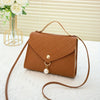 A brown beaded square crossbody bag with a gold chain and leather strap resting on a white surface.