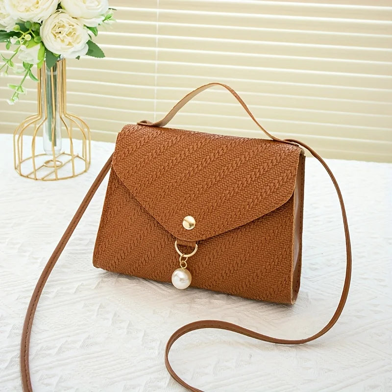 A brown beaded square crossbody bag with a gold chain and leather strap resting on a white surface.