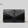 Black alligator pattern leather clutch bag displayed flat on a light gray background.