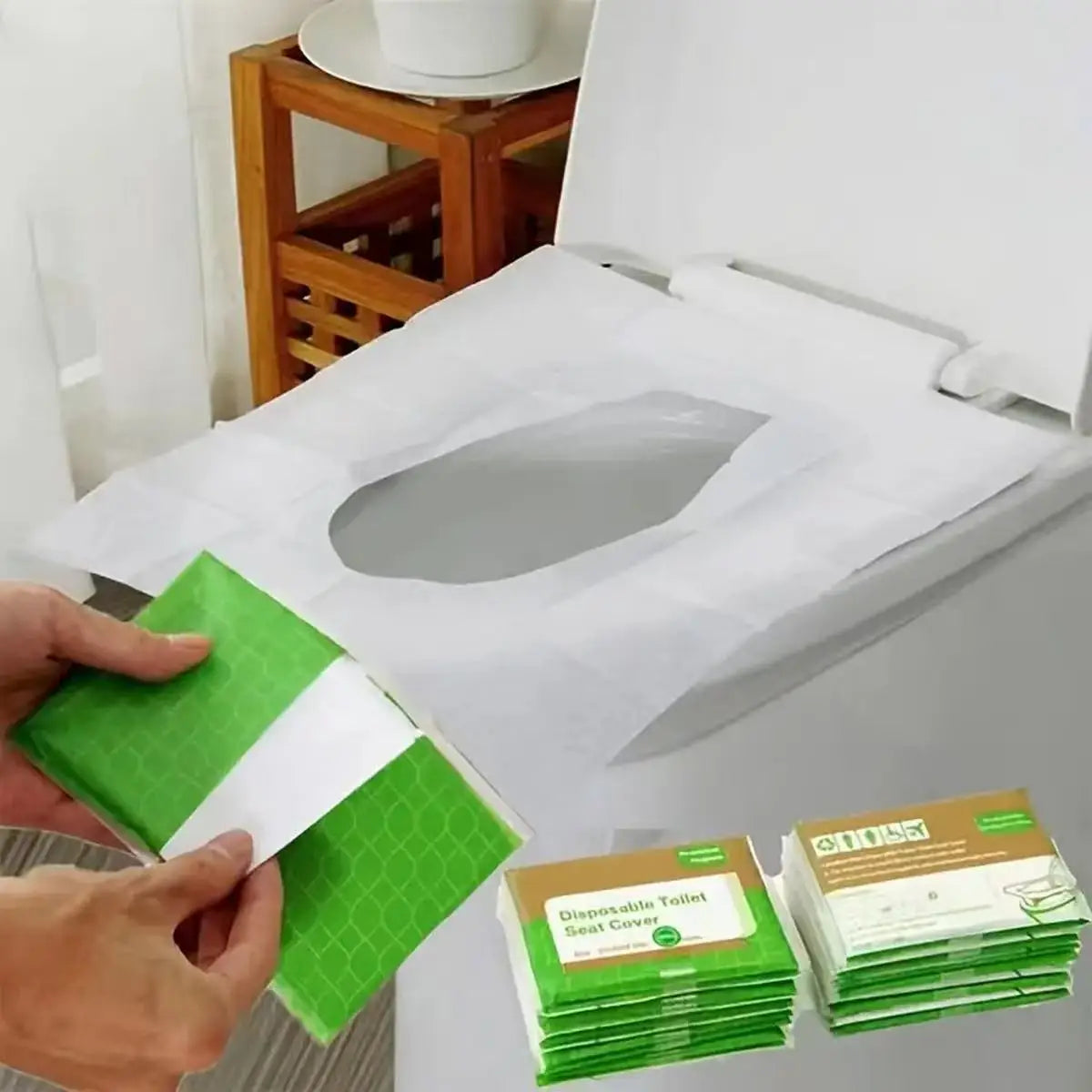 A hand holds a stack of green and white disposable toilet seat covers next to an open toilet seat cover dispenser.