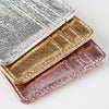 A stack of three slim leather mini wallets or card holders in silver, gold, and rose gold tones.