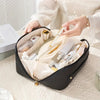 A black vintage floral waterproof makeup tote bag is open, showing various cosmetic and beauty products inside.