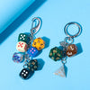 A set of colorful dice charms attached to a silver keychain ring against a light blue background.