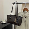 A dark brown leather tote bag with gold hardware is hanging on a metal rack.