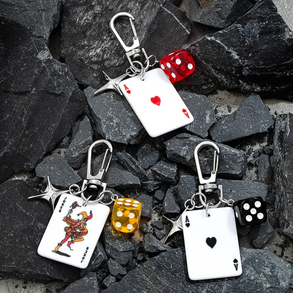 Un juego de dados y cartas de póker retro con llaveros plateados sobre rocas oscuras.
