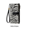 A black and white zebra stripe trifold clutch wallet with a gold-toned strap.