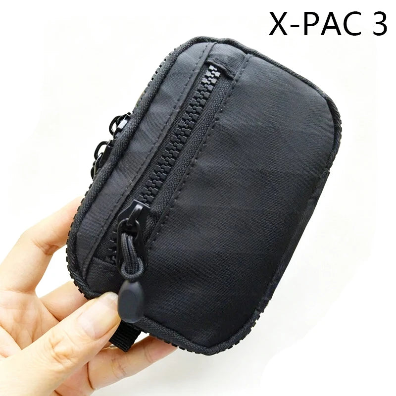 Pochette utilitaire noire X-PAC 3 pour clés et essentiels tenue par une main.