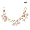 Accesorio de cadena tono dorado con detalles de corazón y flor de cerezo en esmalte.