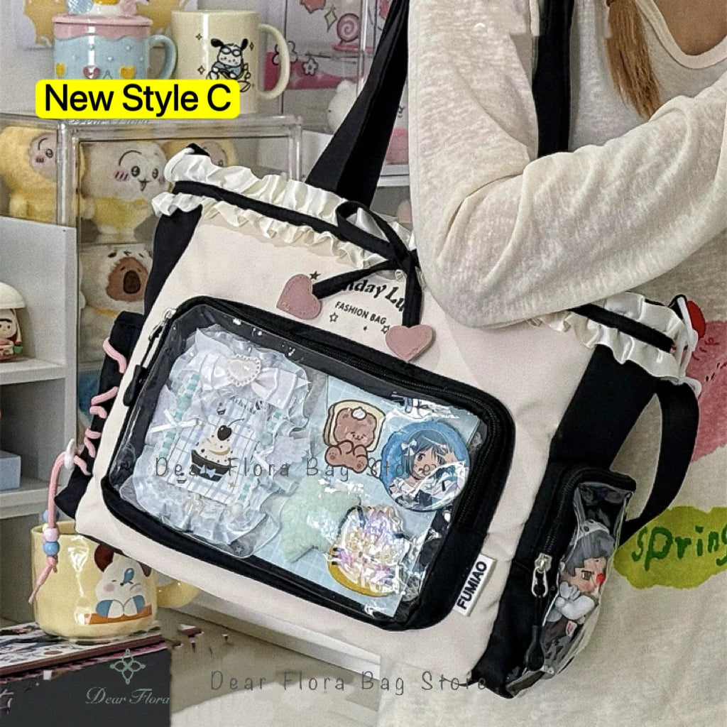 A white transparent shoulder tote bag with black trim and floral accents is displayed next to various small items.