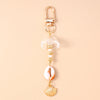 Gold-toned starfish keychain featuring a clear dome and pearl accents on a light pink shell.
