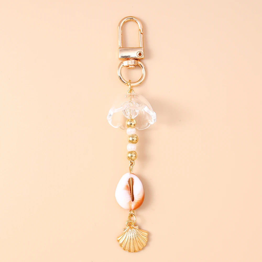 Gold-toned starfish keychain featuring a clear dome and pearl accents on a light pink shell.