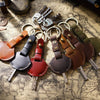 A collection of genuine leather key fob covers and keychain rings scattered on an old map background.
