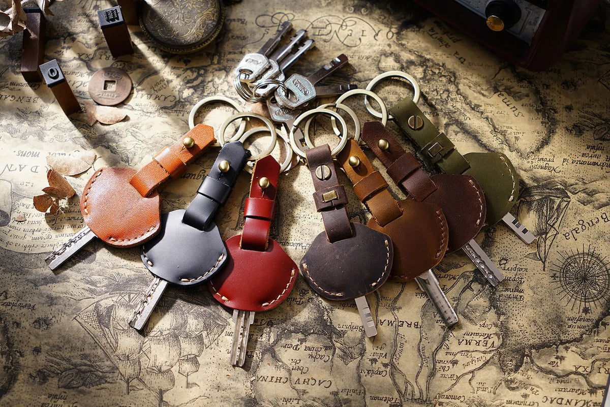 A collection of genuine leather key fob covers and keychain rings scattered on an old map background.