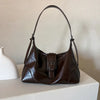 A dark brown retro PU leather underarm bag with a thin strap resting on a white surface.