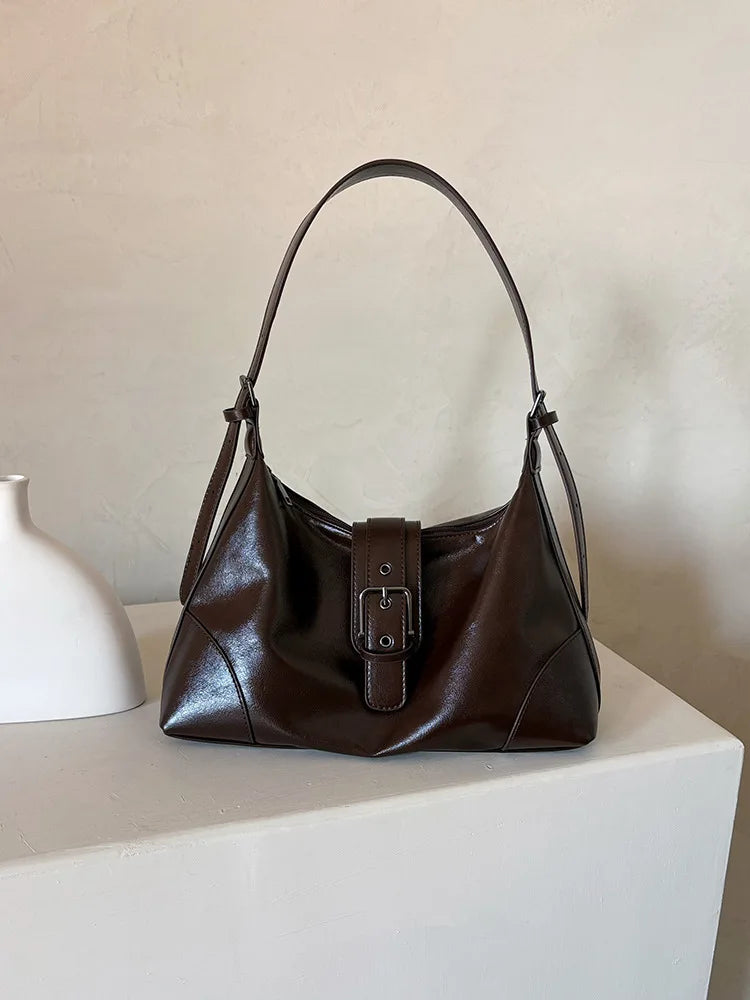 A dark brown retro PU leather underarm bag with a thin strap resting on a white surface.