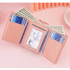 A pink PU leather women's wallet displaying various credit cards and cash inside.