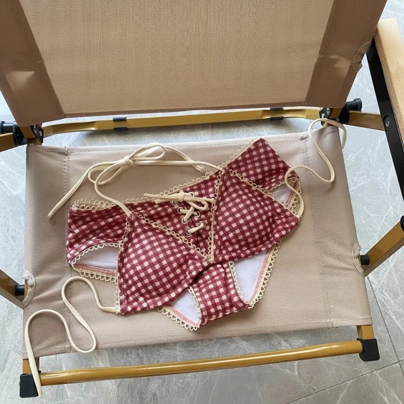A red plaid bikini set with a halter push-up top and low-rise waist is displayed on a light-colored wooden rack.
