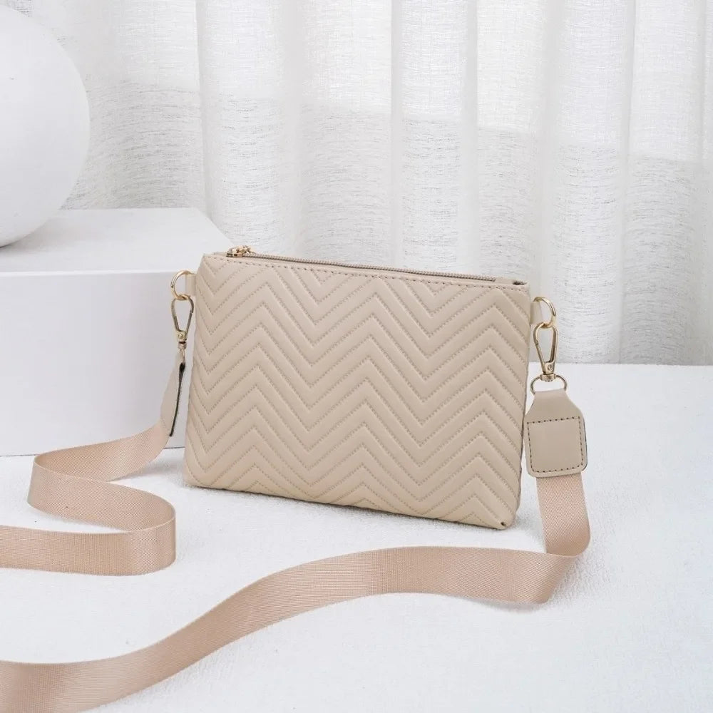 A beige quilted leather crossbody bag with a gold chain strap resting on a white surface.